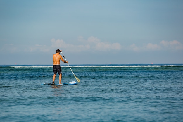 Free photo man riding sup.