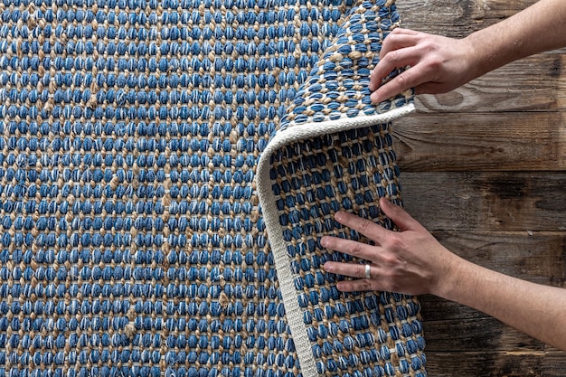 Free photo man rolling hand woven geometric denim area rug on a wooden floor at home