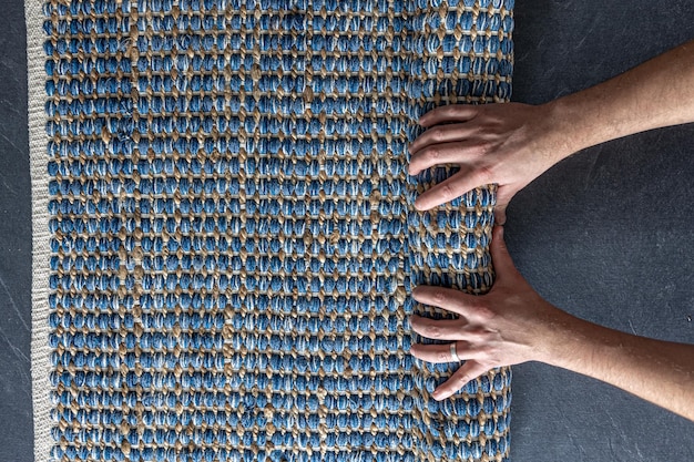 Man rolling hand woven geometric denim area rug on a wooden floor at home