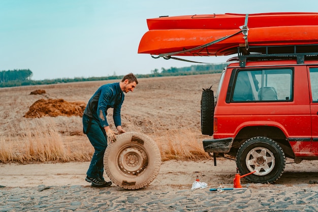 Free photo man rolls a new replacement wheel to 4x4 off road truck