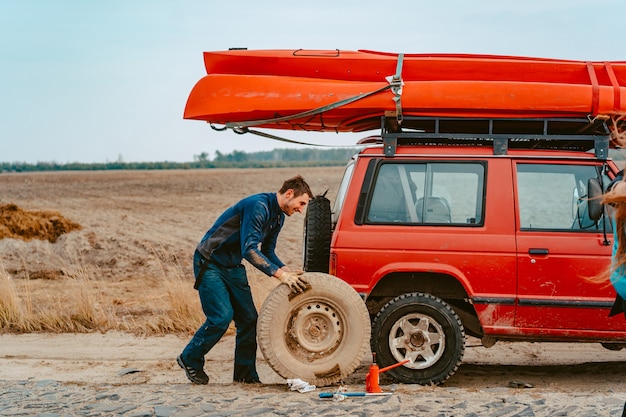 Man rolls a new replacement wheel to 4x4 off road truck