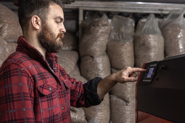 A man in a room with a solid fuel boiler, working on biofuel, economical heating.