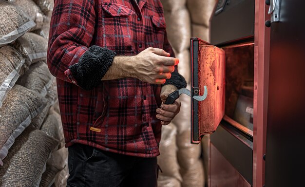 A man in a room with a solid fuel boiler, working on biofuel, economical heating.