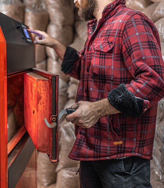 A man in a room with a solid fuel boiler, working on biofuel, economical heating.