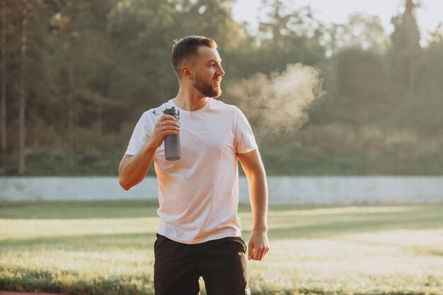 Man runner drinking water at stadium