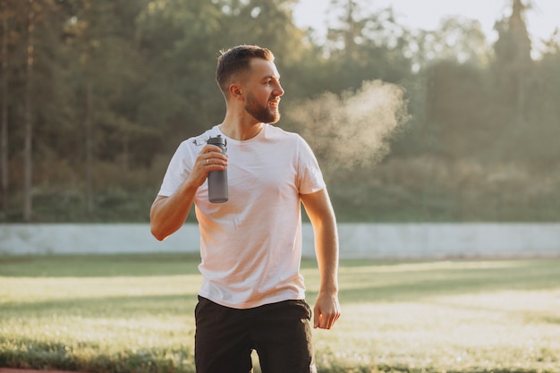 Man runner drinking water at stadium