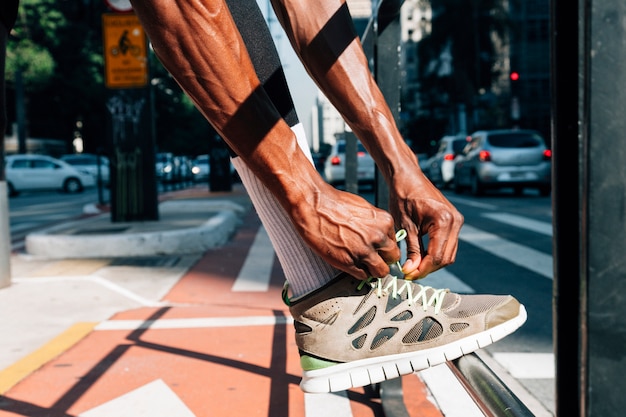 Man runner tying lace of shoes for sport training on road