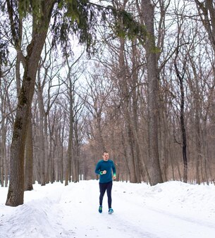 Man running in snow forest in winter. sportsman runner.