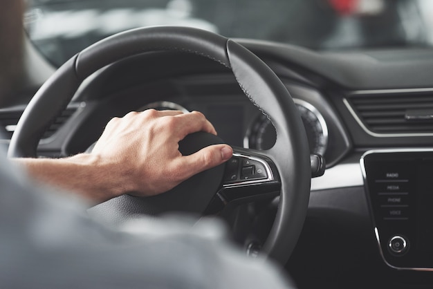 Man's big hands on a steering wheel while driving a car.