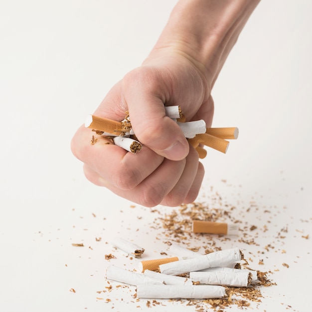 Man's fist creasing cigarettes on a white background