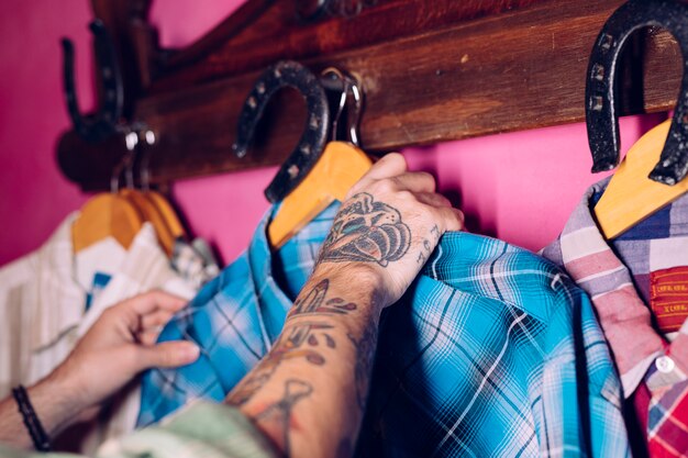 Man's hand hanging the blue plaid shirt on coat rack hook