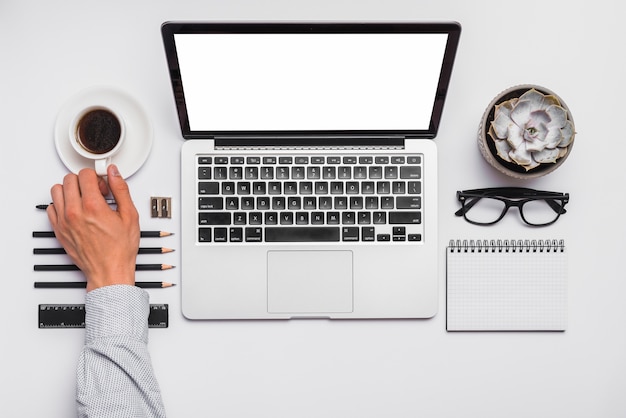 Foto gratuita tazza di caffè della tenuta della mano dell'uomo sulla scrivania con gli articoli per ufficio sistemati