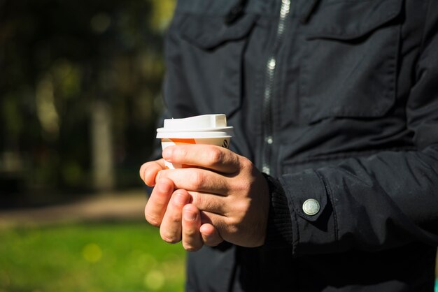 使い捨てのコーヒーカップを持っている男の手