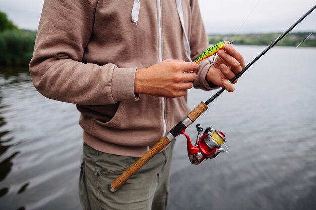 Man's hand holding fishing lure and rod