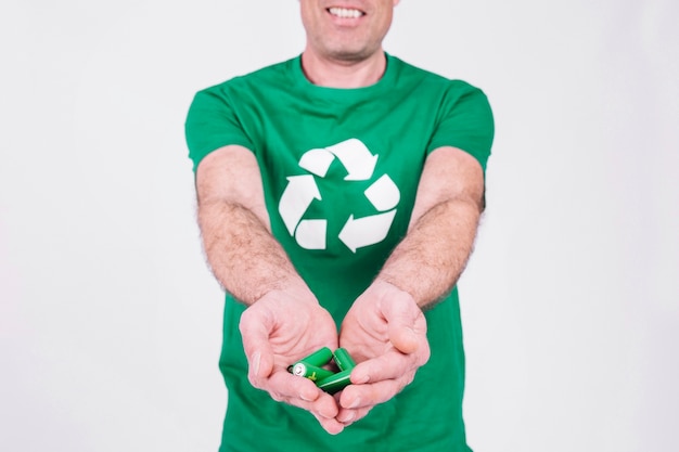 Man's hand holding green batteries