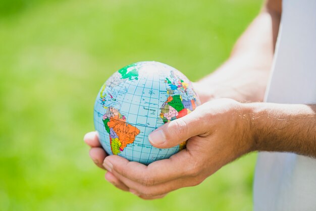 man's hand holding small globe