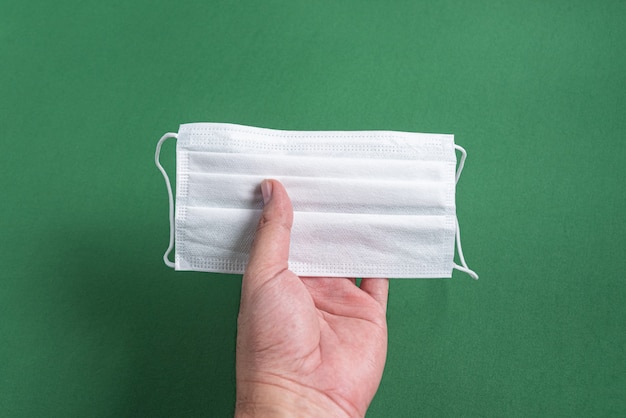 Man's hand holding surgical mask