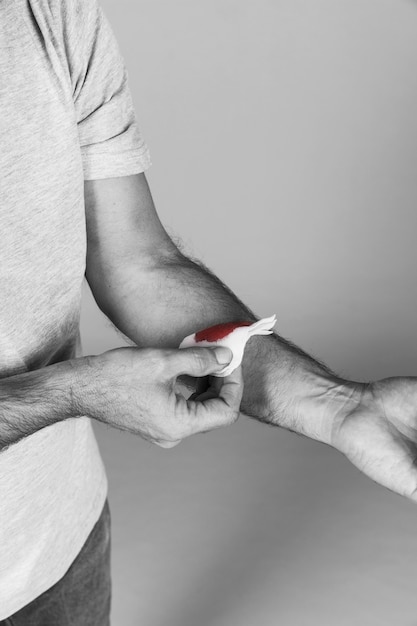 Man's hand holding white medical bandage on bleeding wrist