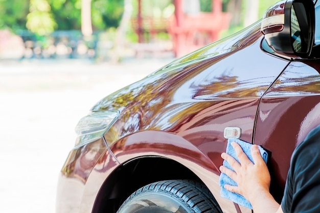 Man's hand is cleaning and waxing the car