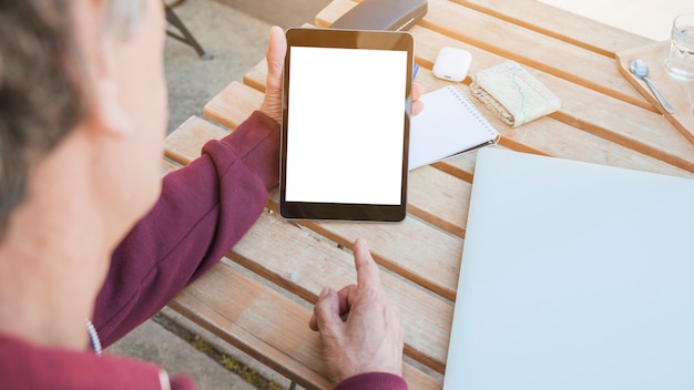 Man's hand pointing finger on digital tablet displaying white screen on wooden desk