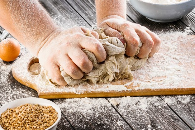 테이블에 그릇에 반죽과 밀 곡물을 준비하는 사람의 손