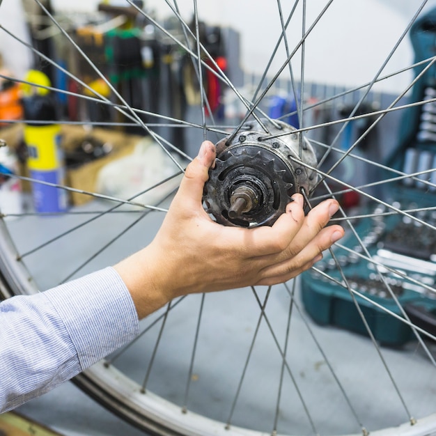 Man's hand repairing bicycle tire in workshop