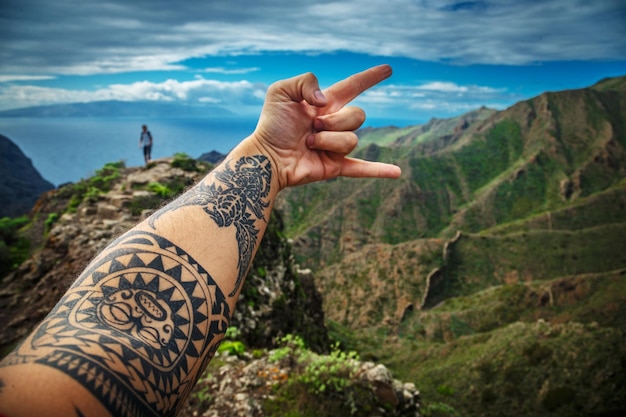 Man's hand showing rock onsign against background of the beautiful mountain landscape