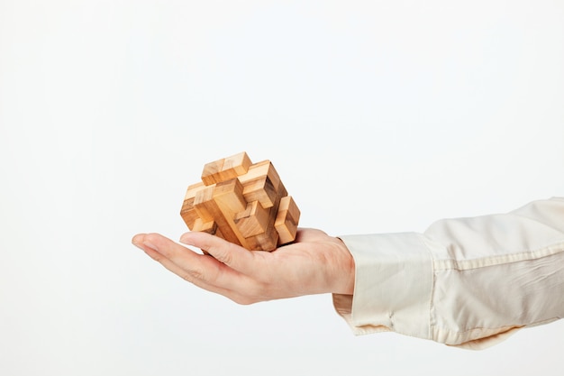 Man's hands holding wooden puzzle.