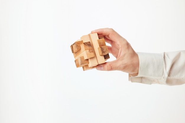 Man's hands holding wooden puzzle.