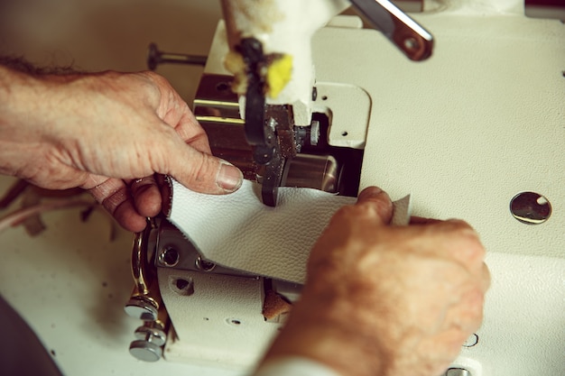 縫製の後ろの男の手。革工房。繊維ヴィンテージ産業。女性の職業の男性。ジェンダー平等のコンセプト