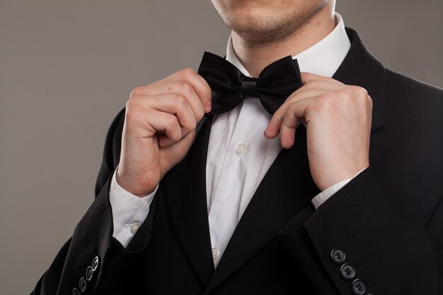 Man's hands touches bow-tie