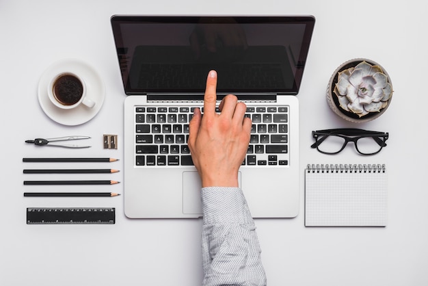 Man's index finger touching on laptop screen in office