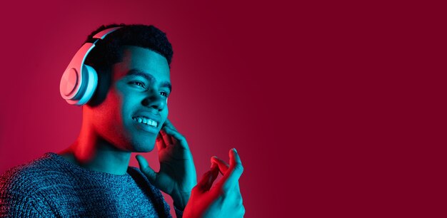 Man's portrait on red studio wall in multicolored neon light