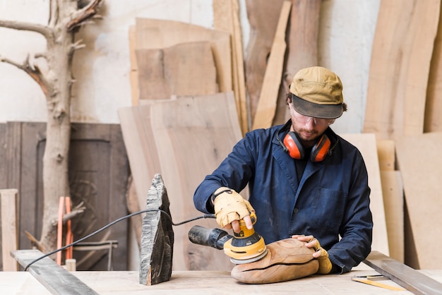 Man sanding a wood with orbital sander in a workshop