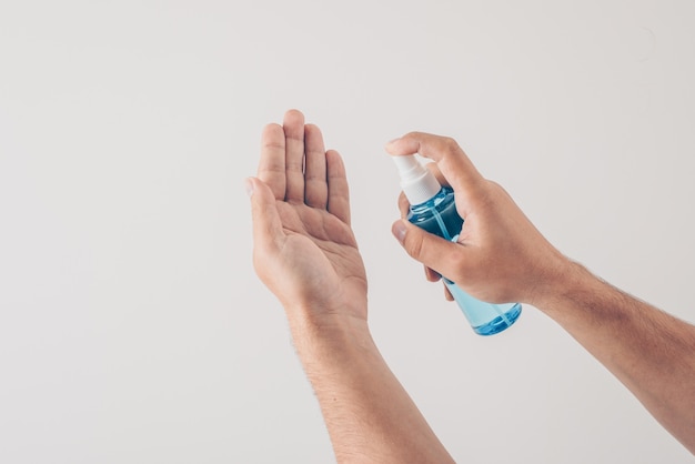 A man sanitizing his hand in white background .  