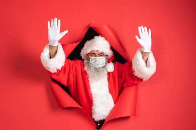 Man in santa costume with medical mask coming out of paper