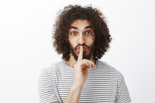 Man saying shh while showing silence gesture with index finger over mouth