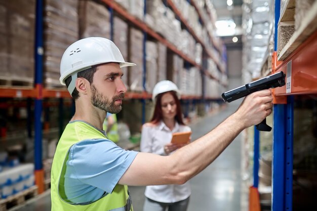 Man scanning barcode from cargo and woman with tablet