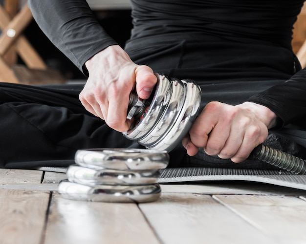 Free photo man setting up discs for dumbbell