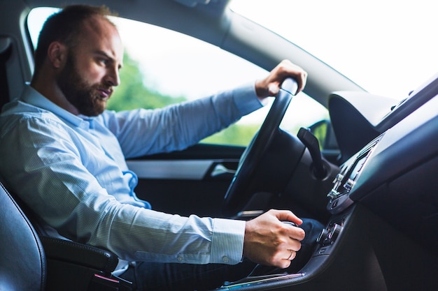 Free photo man shifting gear stick while driving car