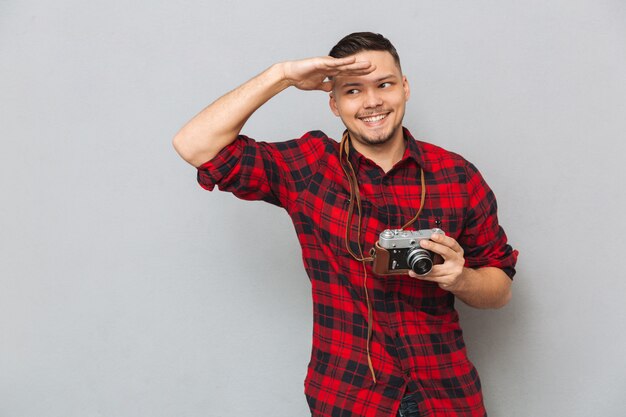 Man in shirt holding retro camera and looking at camera