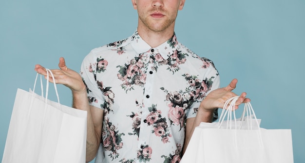 Free photo man in shirt holding shopping bags in both hands