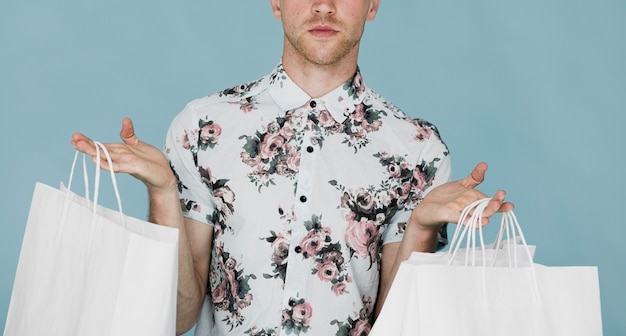 Man in shirt holding shopping bags in both hands