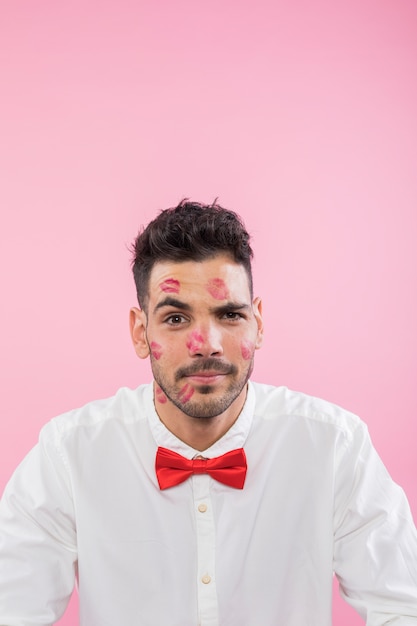 Uomo in camicia con segni di bacio rossetto sul viso