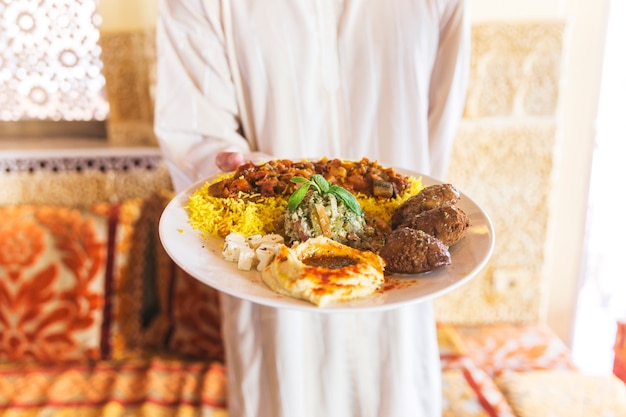 Человек показывает блюдо из арабской пищи