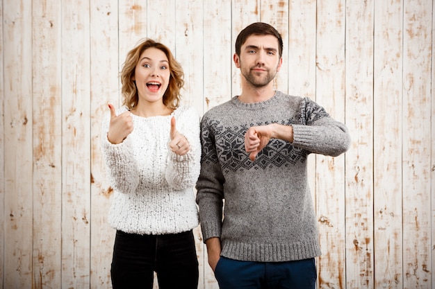 Man showing dislike girl with thumb up over wooden wall