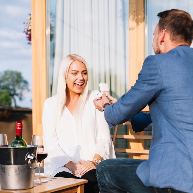 Man showing an engagement ring to his amazed girlfriend in a restaurant