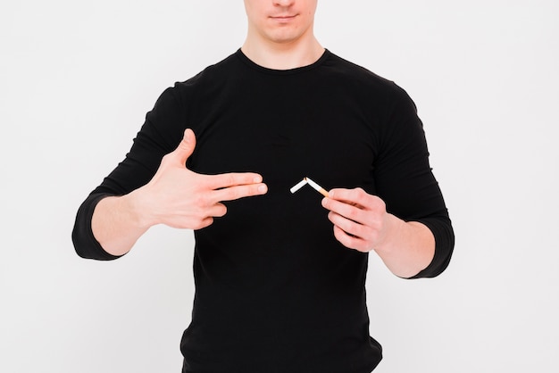 Free photo man showing gun gesture near the broken cigarette