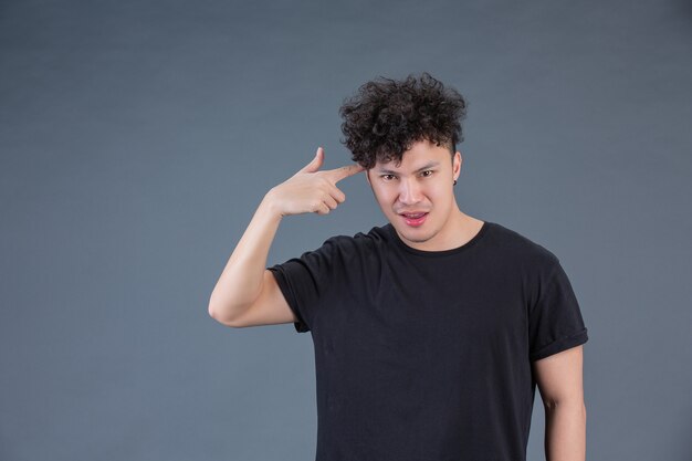 Man showing hand gesture in studio behind posing