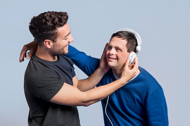 Free photo man showing his friend a song through headphones